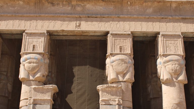 Hathor-headed columns and carved reliefs framing the entrance of the Temple of Hathor at Dendera.
